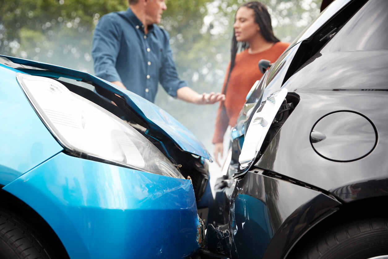 Drivers standing between two damaged vehicles following an accident, illustrating a scenario where critical mistakes can be made.