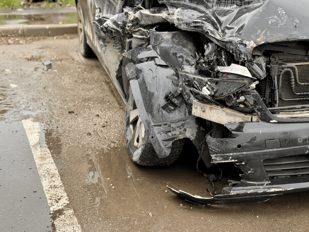 Severely damaged black car after a front-end collision.